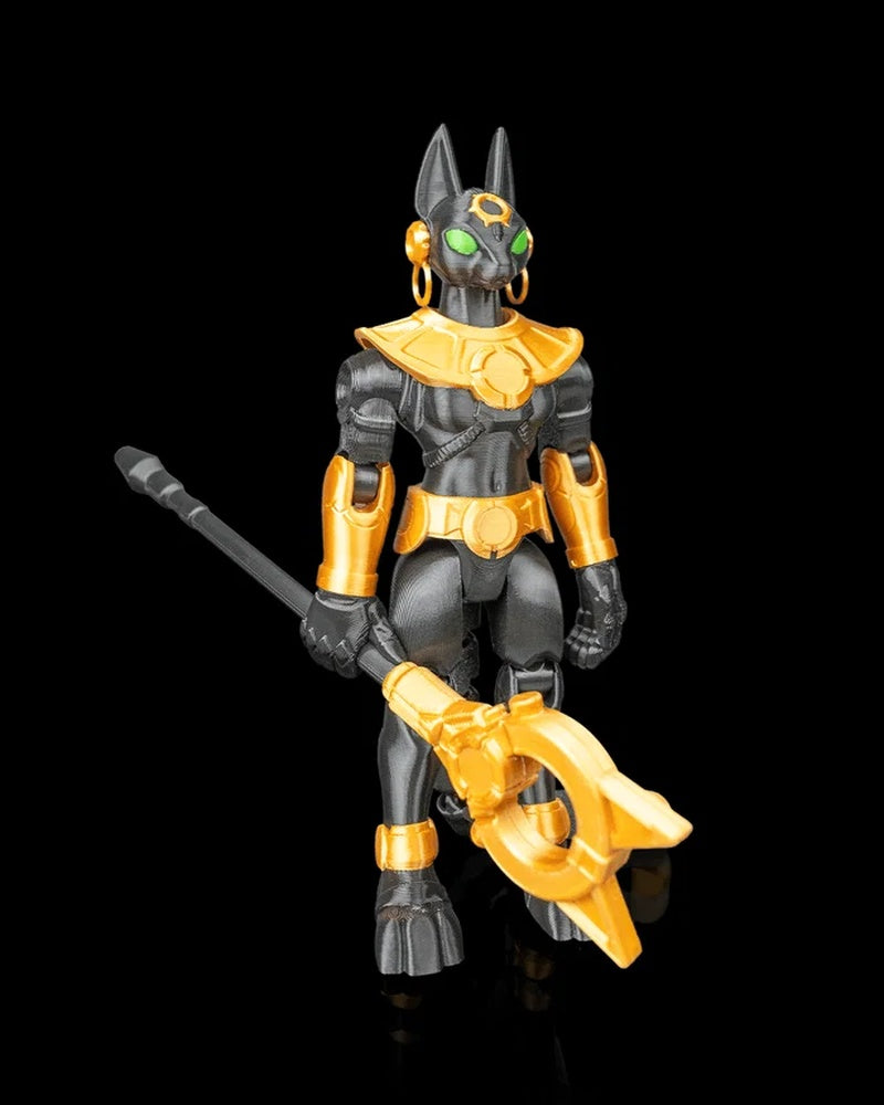 Angled front view of a black-and-gold cat-headed figurine with green eyes and ring earrings holding a staff.
