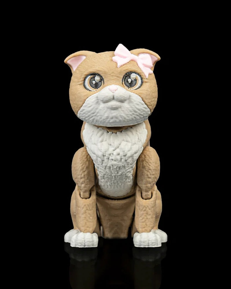 Front view of a tan and white cat figurine with large eyes and a pink bow on a black background