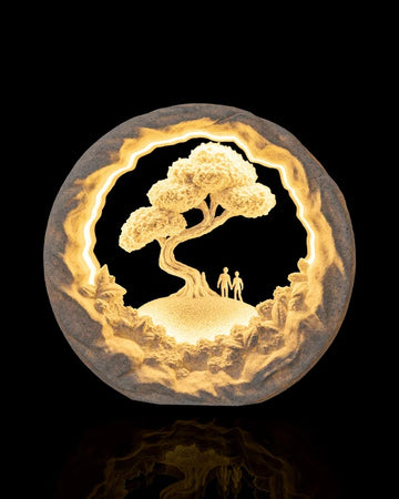 Round illuminated table lamp with a tree, rocky border, and two small figures on a black background