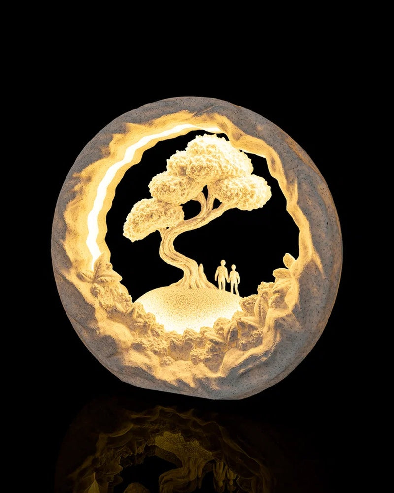 Round glowing tree scene lamp viewed from a slight angle on a dark reflective surface