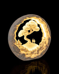 Illuminated circular landscape lamp with a tree and two small standing figures
