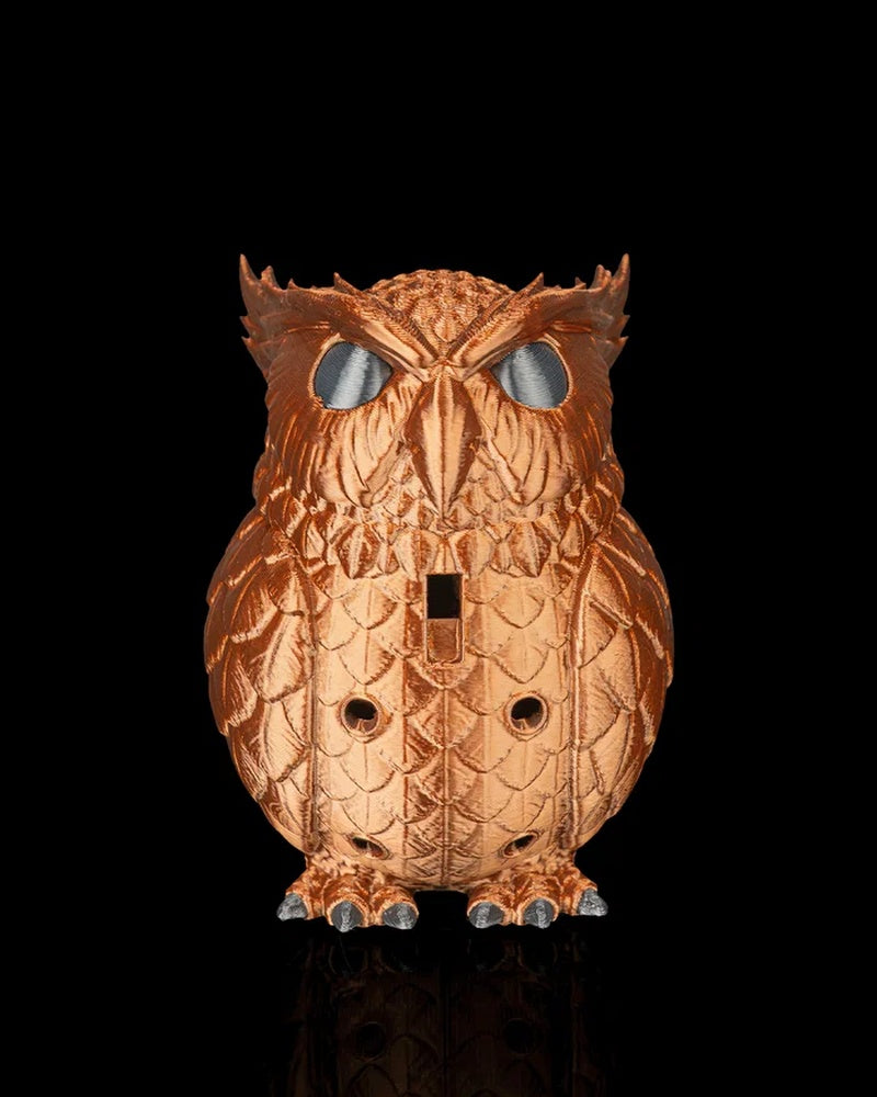 Front view of a copper-colored owl figurine with large silver eyes, feather texture, front openings and gray claws on a black background