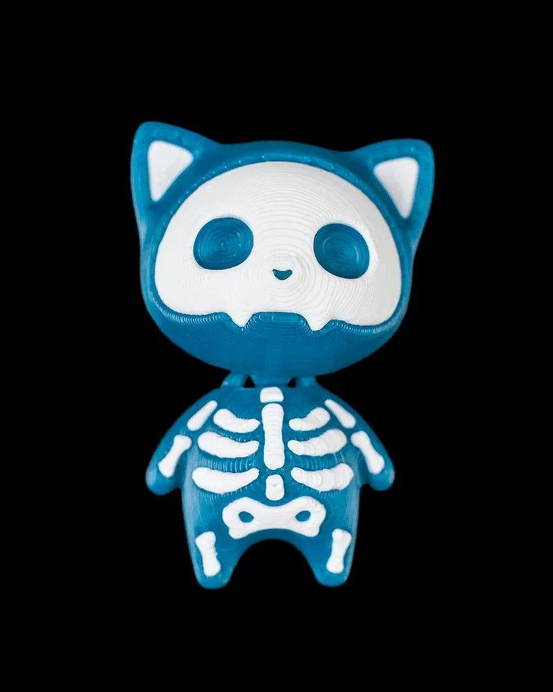 Blue cat figurine with white skull face and skeleton markings on a black background
