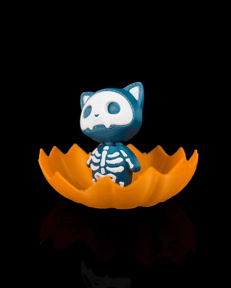 Side view of a blue skeleton cat figurine inside an orange jagged pumpkin shell