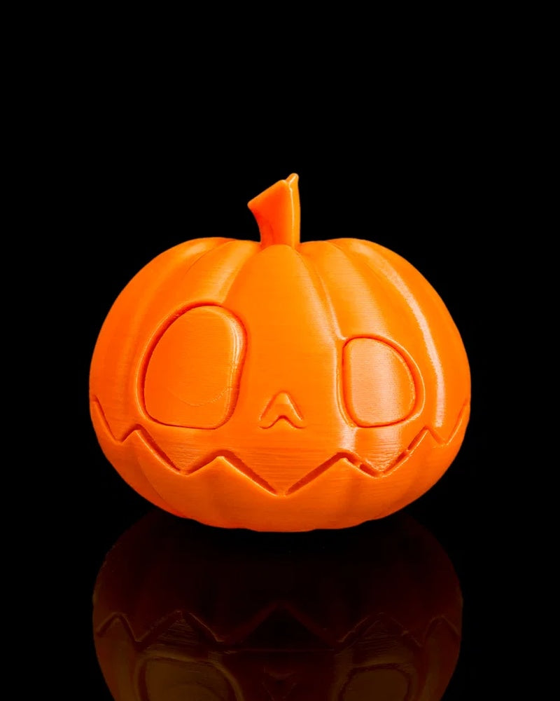 Orange pumpkin with raised face details and a small stem on a black background