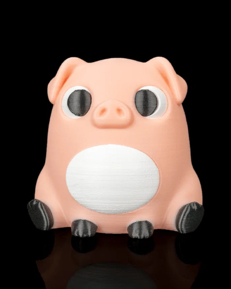 A peach pig figure with black eyes, white belly, floppy ears, and dark hooves sits on a black reflective surface.