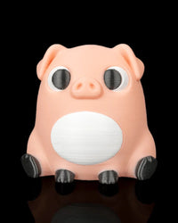 A peach pig figure with black eyes, white belly, floppy ears, and dark hooves sits on a black reflective surface.