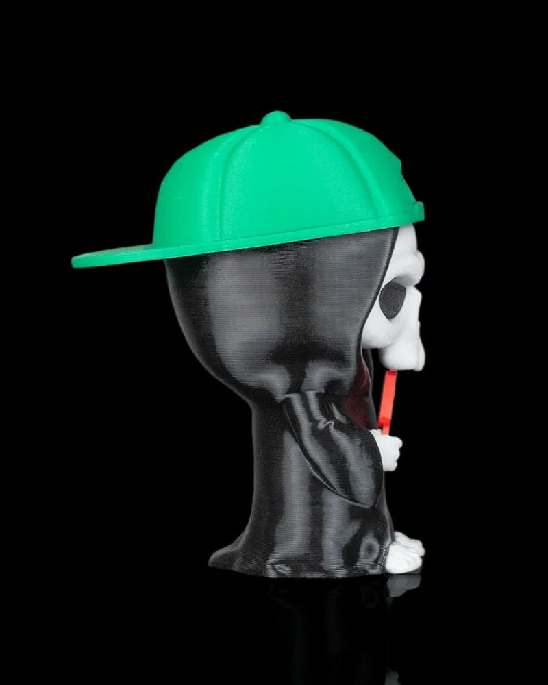 Side view of a hooded skull figurine in a black robe wearing a green cap