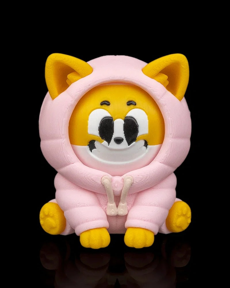 Front view of a yellow and white dog figurine in a pink hood with a smiling face on a black background.