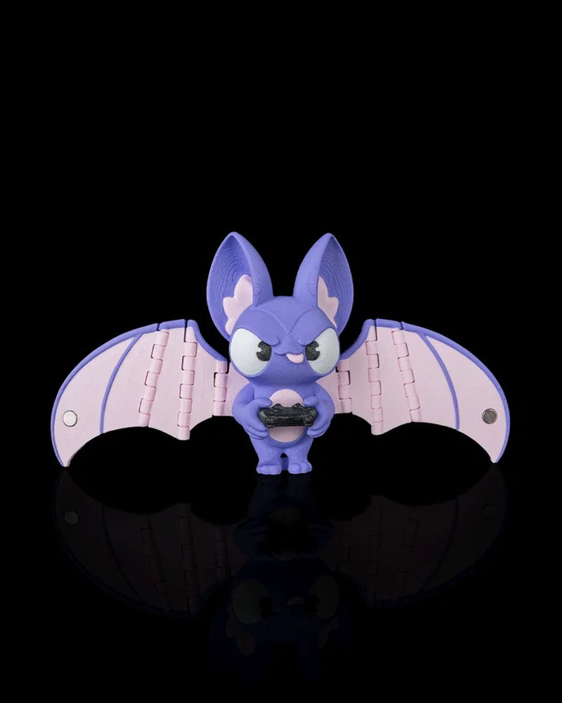 Purple bat figurine with pale pink wings holding a small black controller on a black background