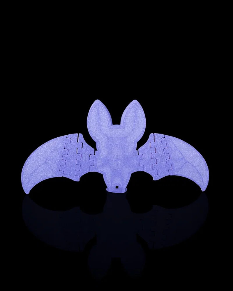 Back view of a purple bat figurine with both wings spread on a black background