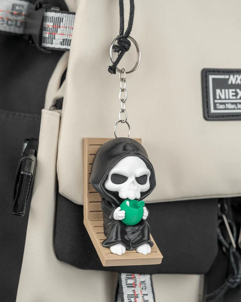 Hooded skull character with a green drink hanging by a metal ring and chain in front of a bag