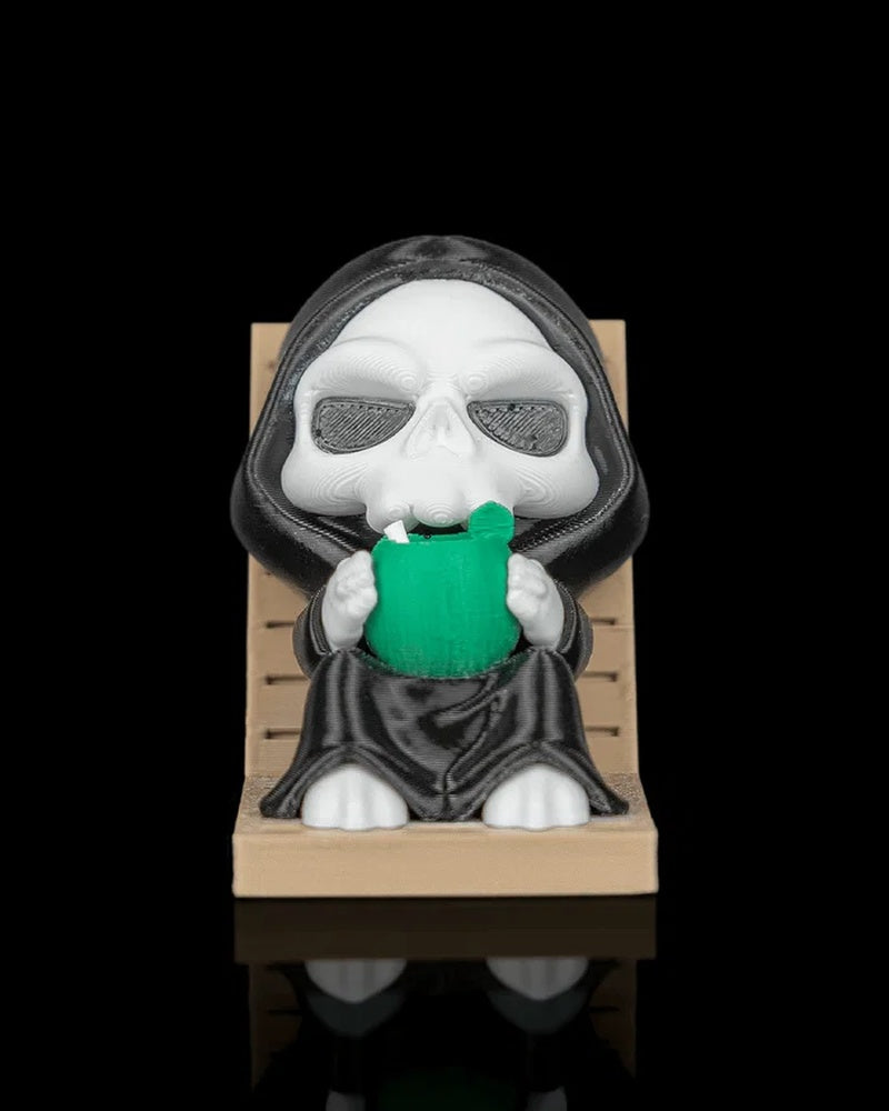 Front view of a hooded skull character seated on a tan lounge chair holding a green drink