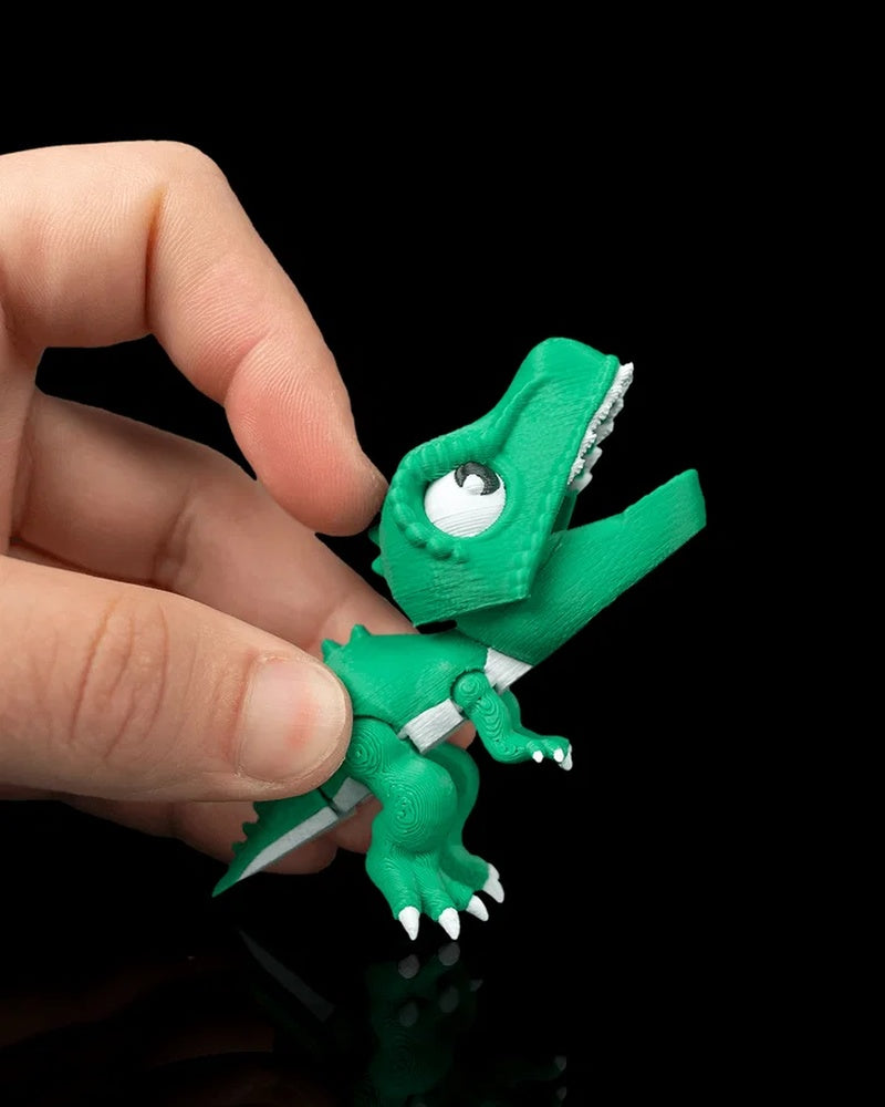 Hand holding a green dinosaur toy with its mouth open on a black background