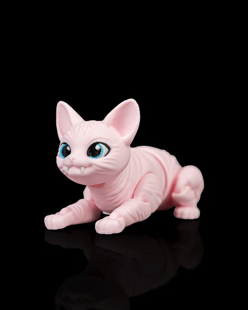 Front angled view of a crouching pink cat figurine with large blue eyes, large ears, and small white fangs on a black surface.