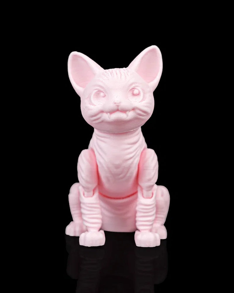 Front view of a pink cat figurine with large ears, raised eye shapes, small fangs, and a seated pose on a black surface.