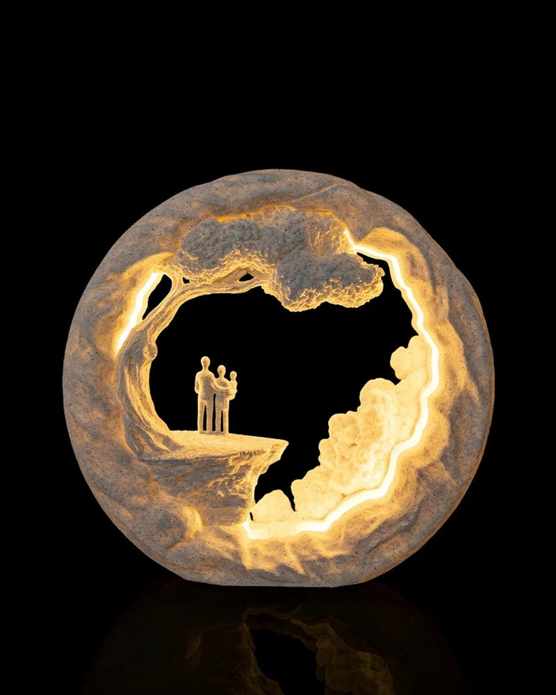 Round glowing table lamp with a cliffside scene and small figures standing on a ledge