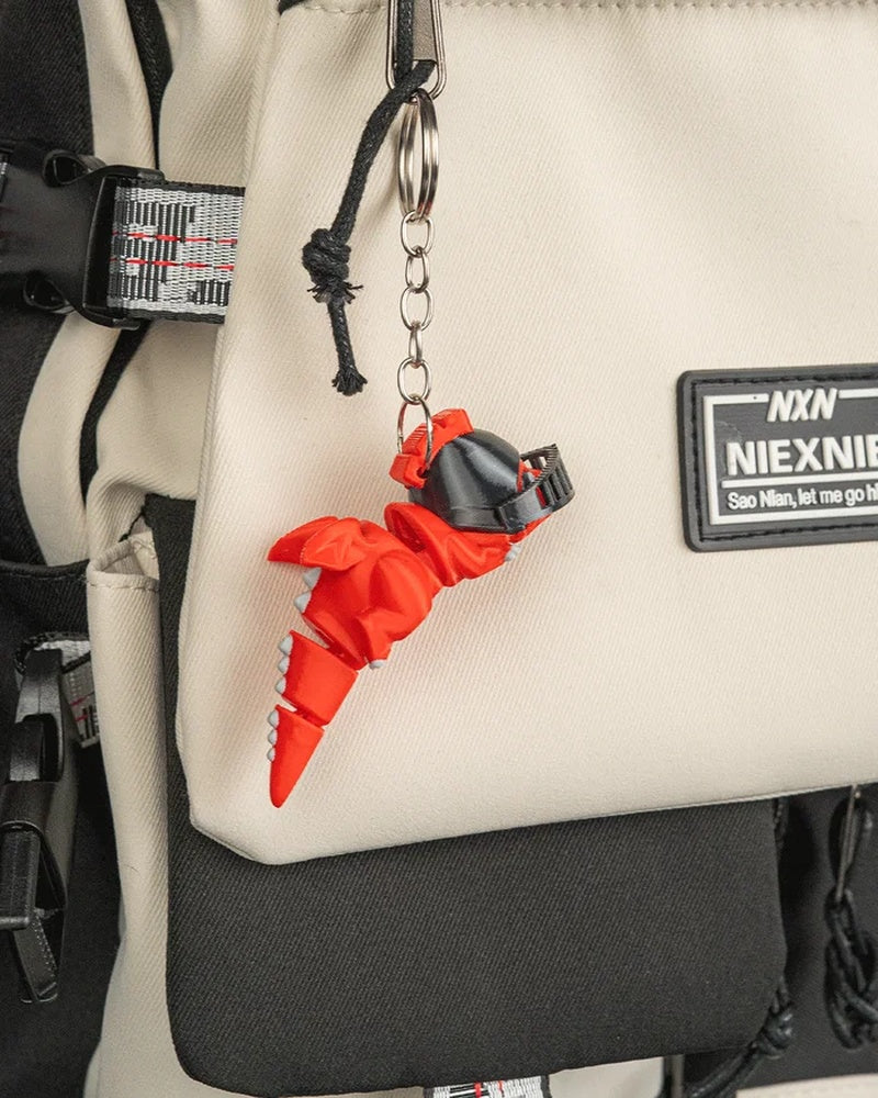 Orange dragon charm hanging by a metal ring and chain from a beige bag
