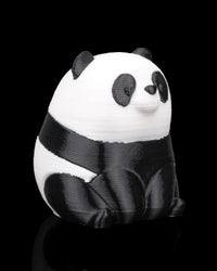 Angled side view of a small black-and-white panda figure on a black background