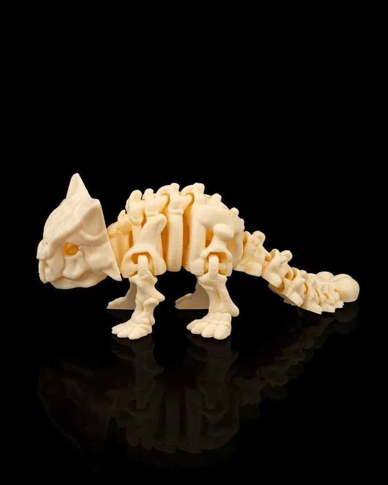 Side view of cream-colored ankylosaurus skeleton-style figurine with long tail on a black reflective surface