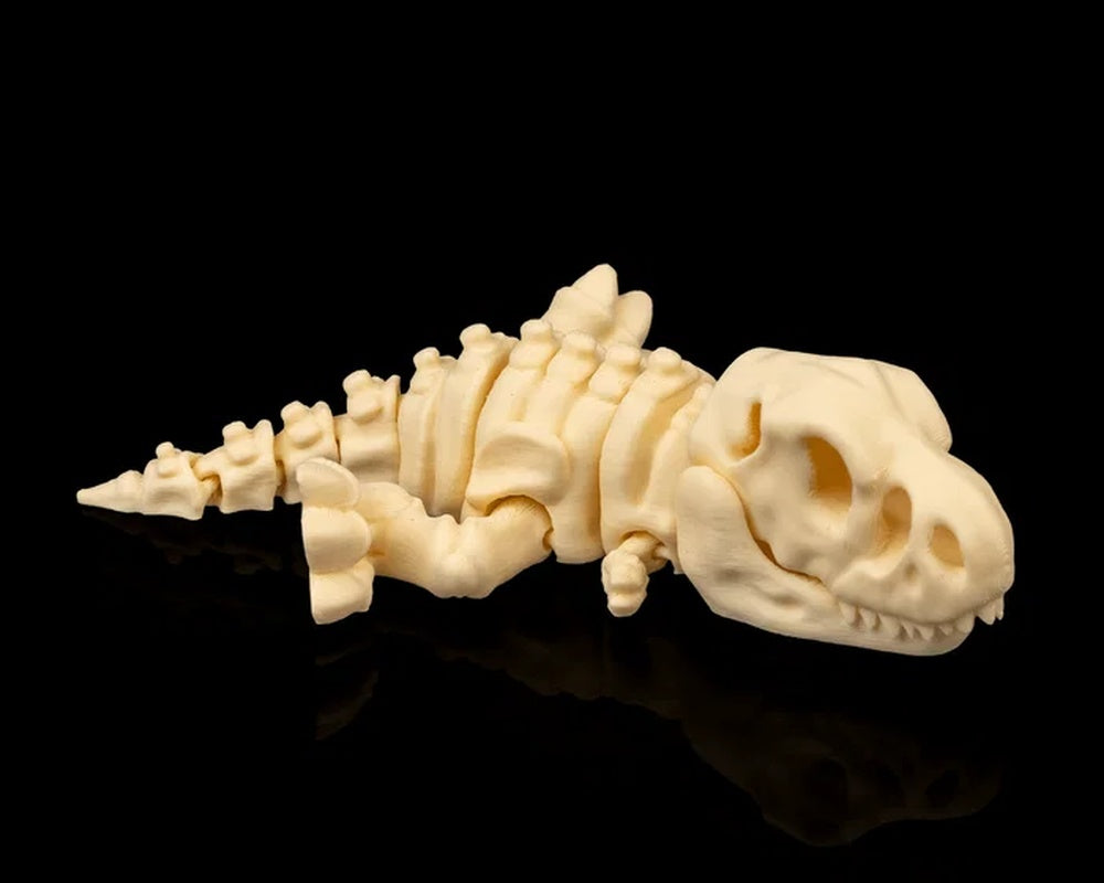 Cream T-Rex skeleton figurine lying on its side on a black reflective surface