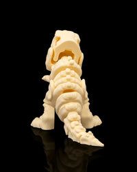 Back view of a cream T-Rex skeleton figurine with skull opening, spine, legs, and tail visible