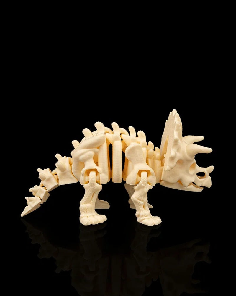 Cream-colored triceratops skeleton figurine shown from the side on a black background