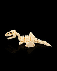 Cream-colored velociraptor skeleton figurine lying on its side on a black reflective surface