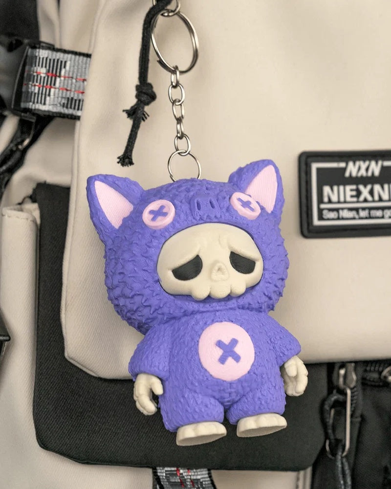 Purple bat-themed skull figure hanging from a metal ring and chain on a bag