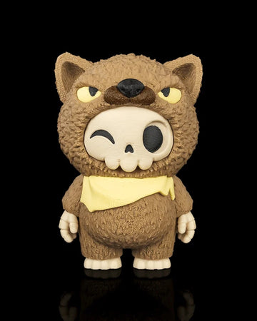 Front view of a brown animal-hood skull figurine with yellow eyes and a yellow scarf on a black background