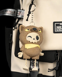 Brown animal-hood skull figurine with dangling legs hanging by a metal ring and chain on a backpack