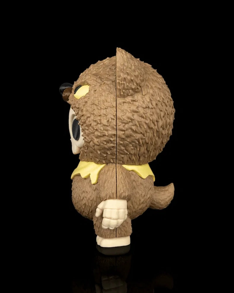 Side view of a brown animal-hood skull figurine with a tail and yellow scarf on a black background