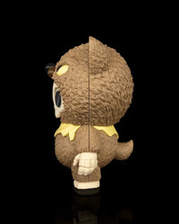 Side view of a brown animal-hood skull figurine with a tail and yellow scarf on a black background
