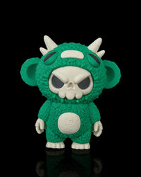Green skull-faced monster toy with white horns and ears on a black background