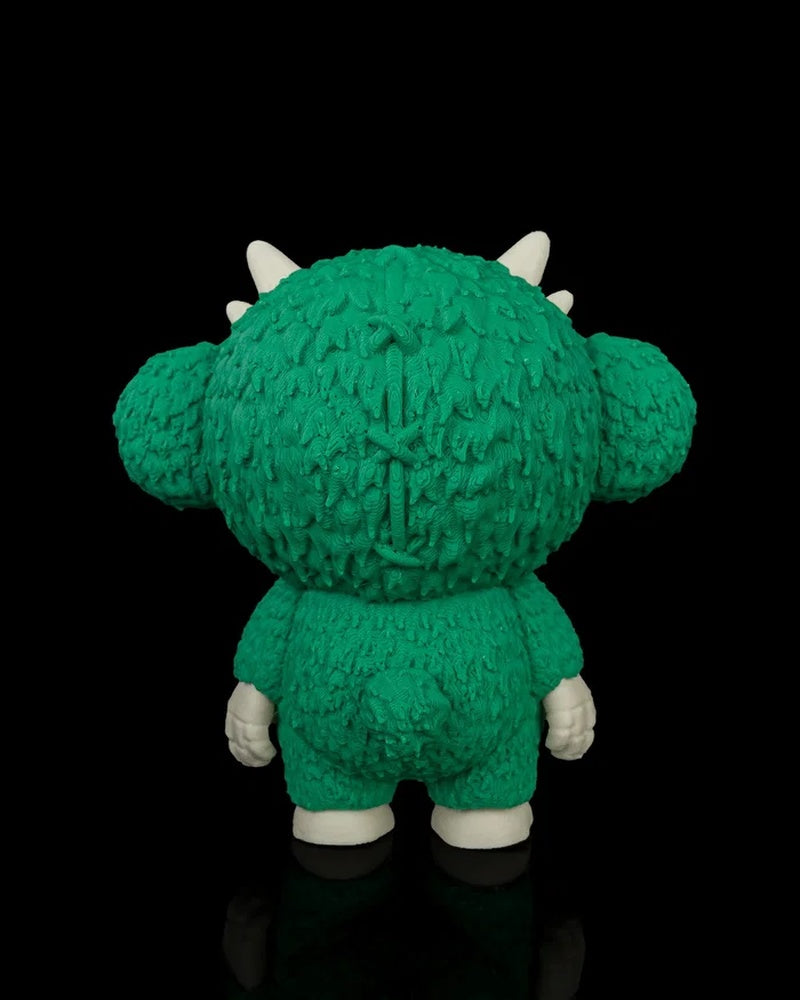 Back view of a green monster toy with large ears, horns, small tail, and white feet