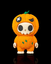Orange pumpkin skull figurine standing on a black background