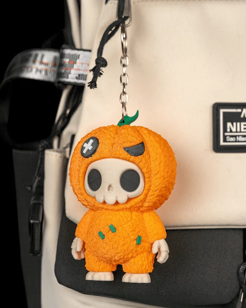 Orange pumpkin skull charm hanging from a bag by a metal ring and chain