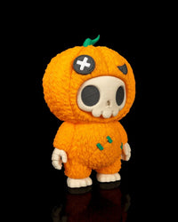 Angled view of an orange pumpkin skull figurine on a black background