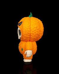 Side view of an orange pumpkin skull figurine on a black background