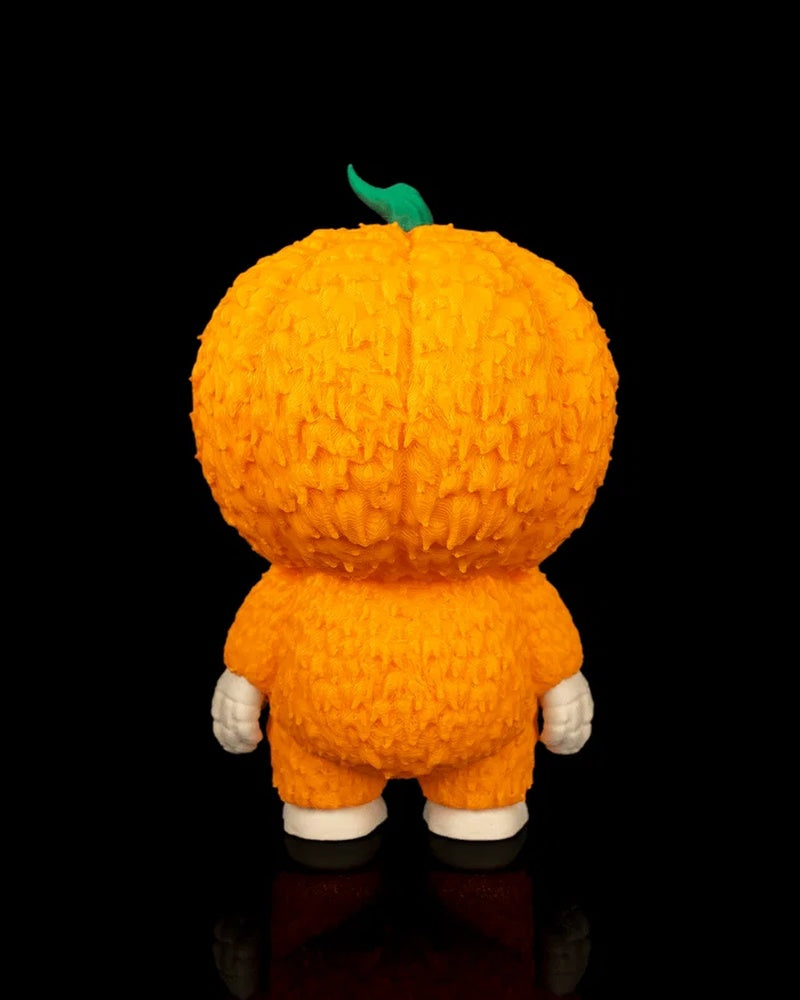 Back view of an orange pumpkin skull figurine with green stem on a black background