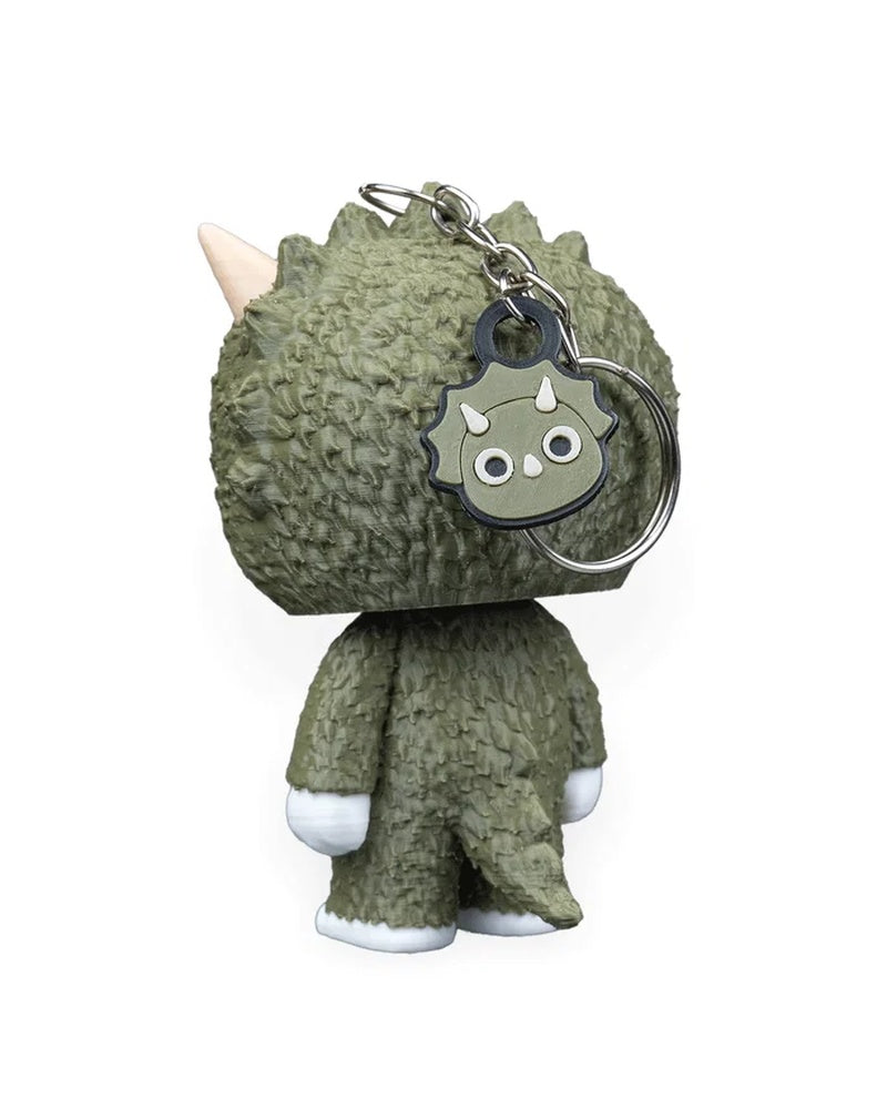 Rear angle of a green horned dinosaur character with a metal ring, chain, and small dinosaur face charm.
