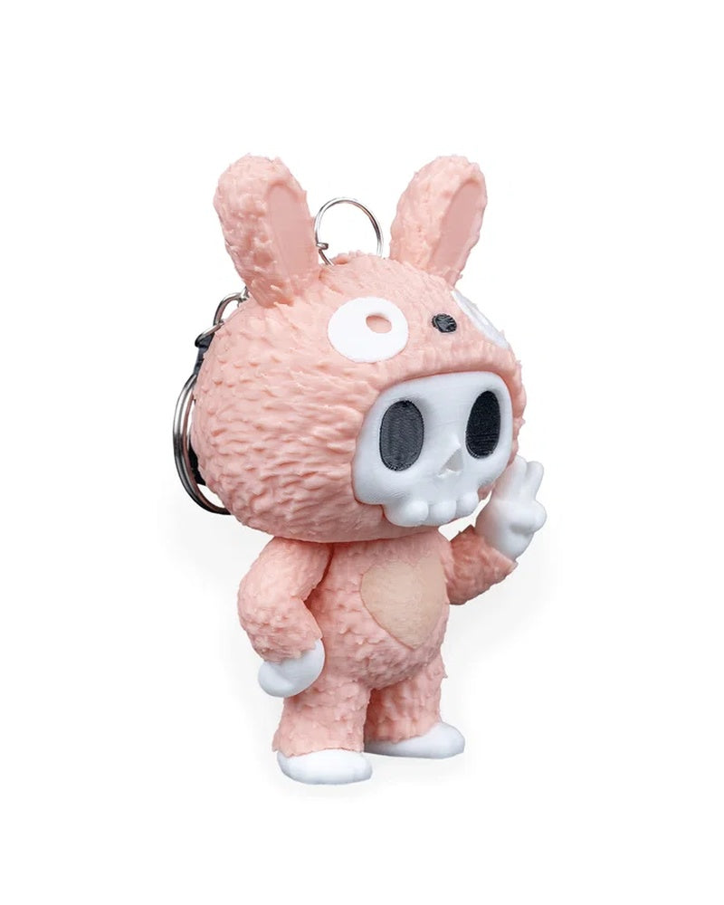 Side front view of a pink bunny-suit skull character with a raised peace-sign hand and metal ring behind it