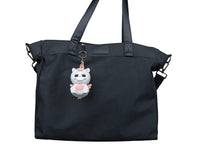 Small white unicorn costume figure hanging from a black bag by a metal ring