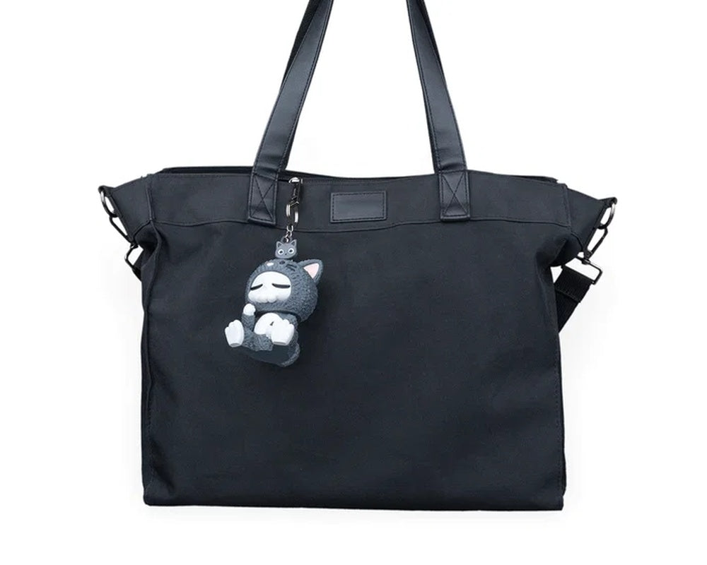 Black duffel bag with a small gray cat character charm hanging from the front zipper