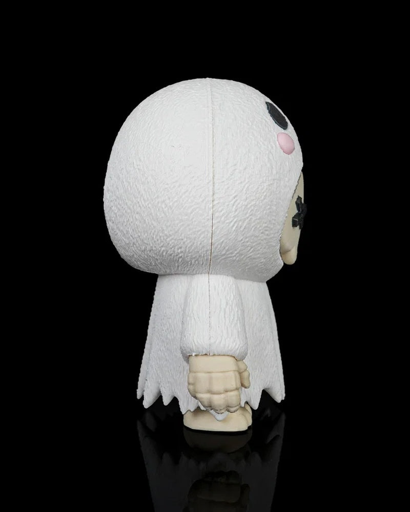 Side view of the white ghost skull figurine showing the rounded hood, small arm, and robe edge on a black background.