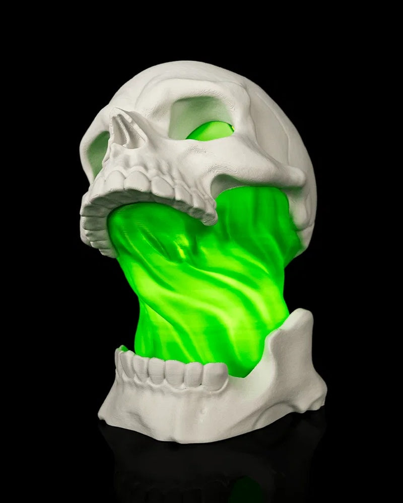 White skull lamp with a bright green illuminated center on a black background