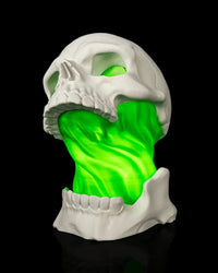 White skull lamp with a bright green illuminated center on a black background