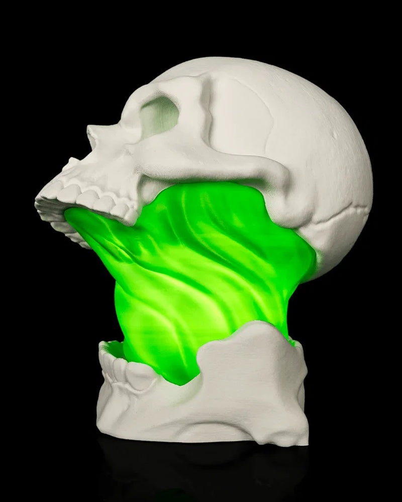 Side view of a white skull lamp with a green glowing center and lower jaw detail