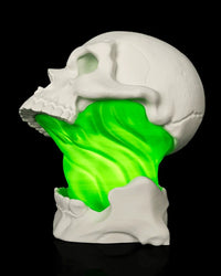 Side view of a white skull lamp with a green glowing center and lower jaw detail