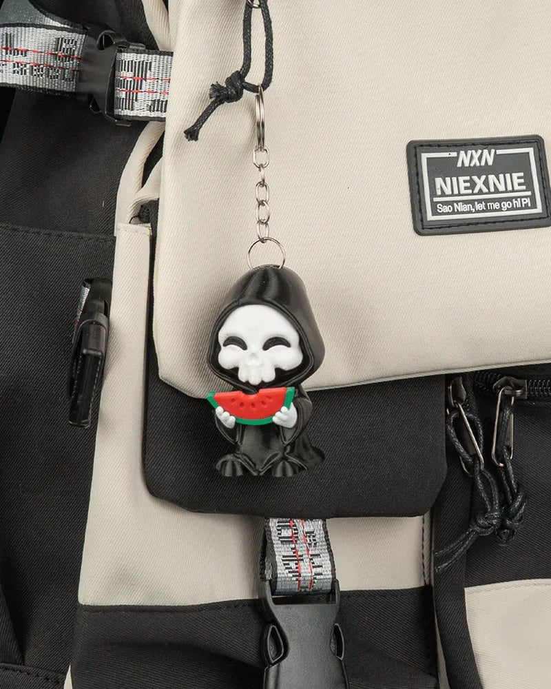Small hooded skull charm hanging from a backpack with a metal ring and chain